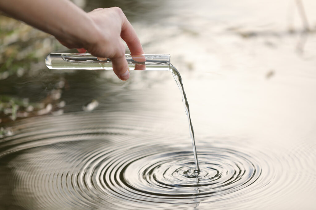 Pond water pollution concept. scientist biologist and researcher takes samples of dirty water from a pond into a test tube.
